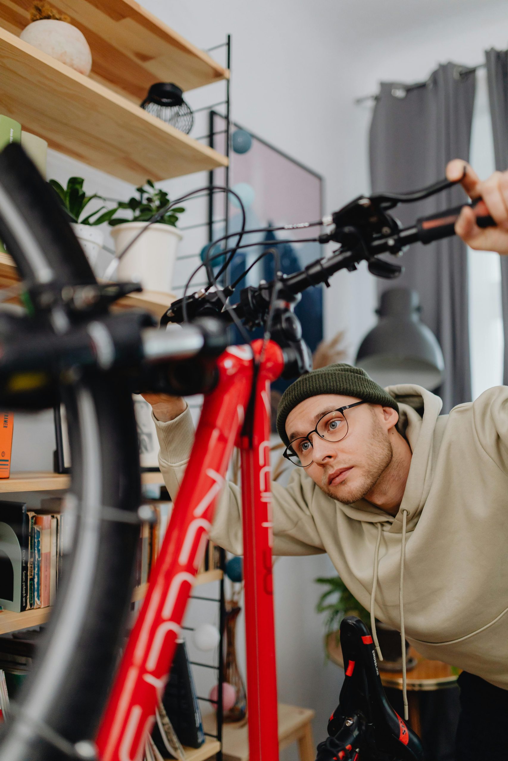 A man in glasses examines a bicycle in a cozy indoor setting.