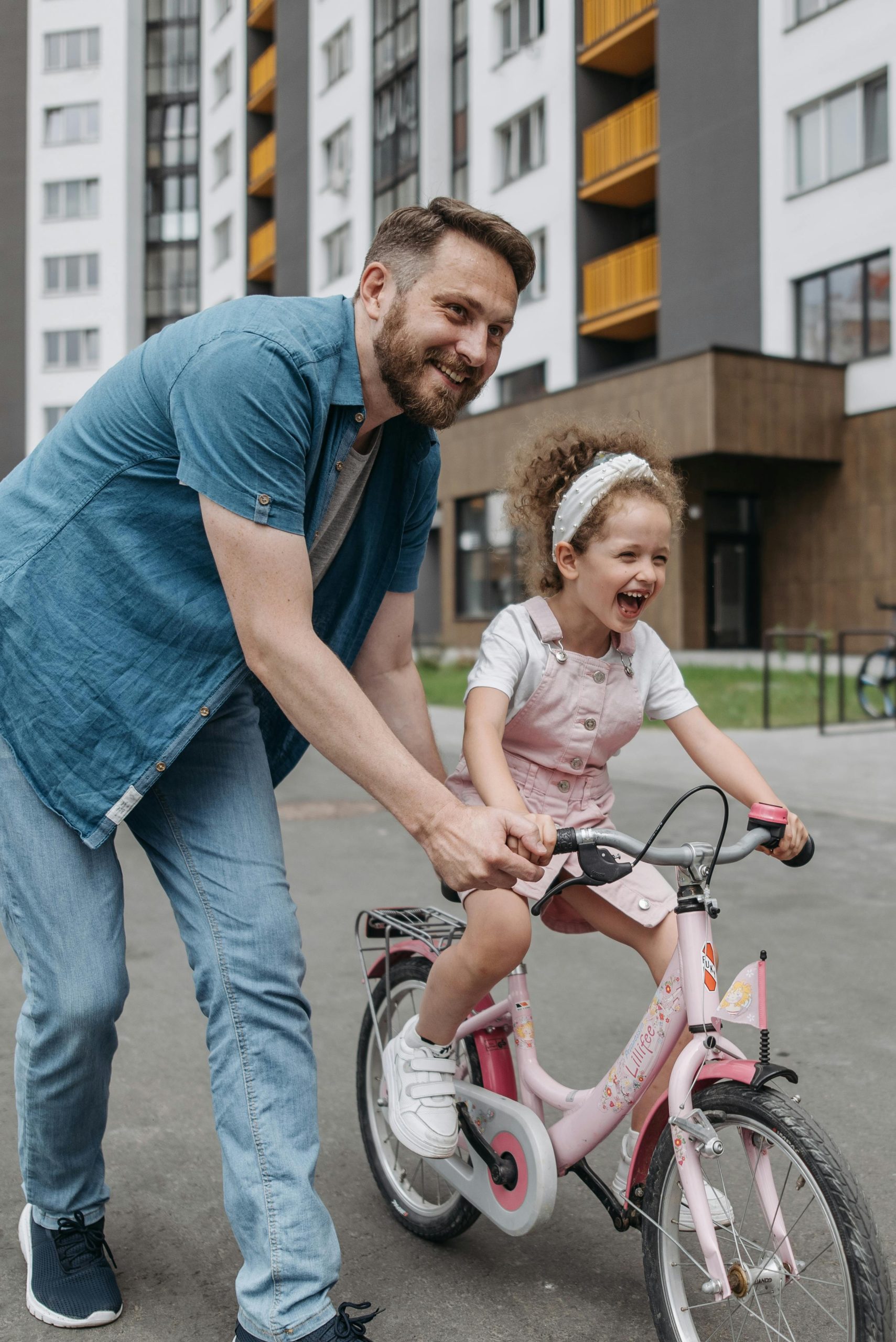 A joyful moment of a father teaching his daughter to ride a bicycle outside.