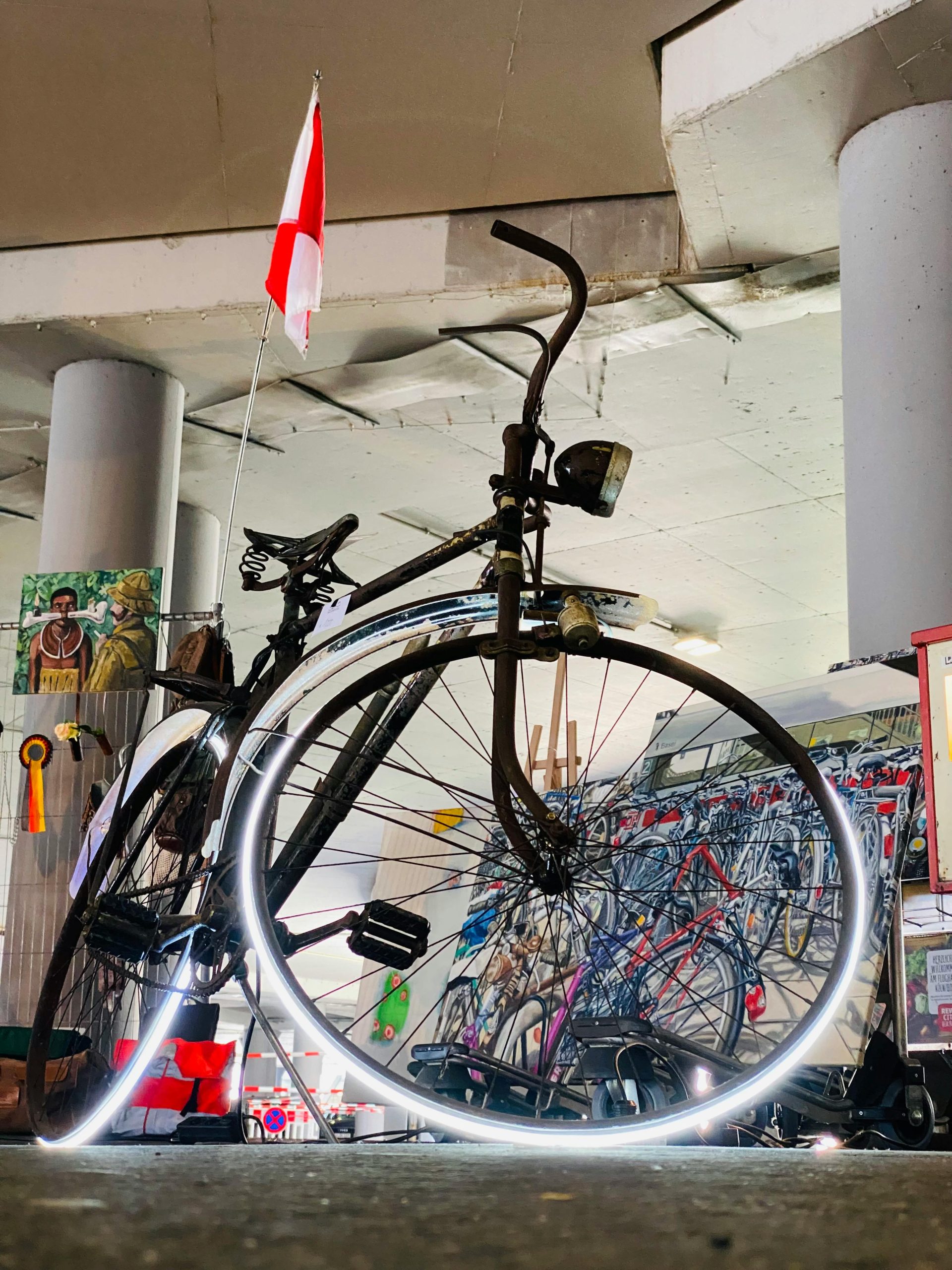 Retro bicycle with illuminated wheel, urban decor, and flag indoors.